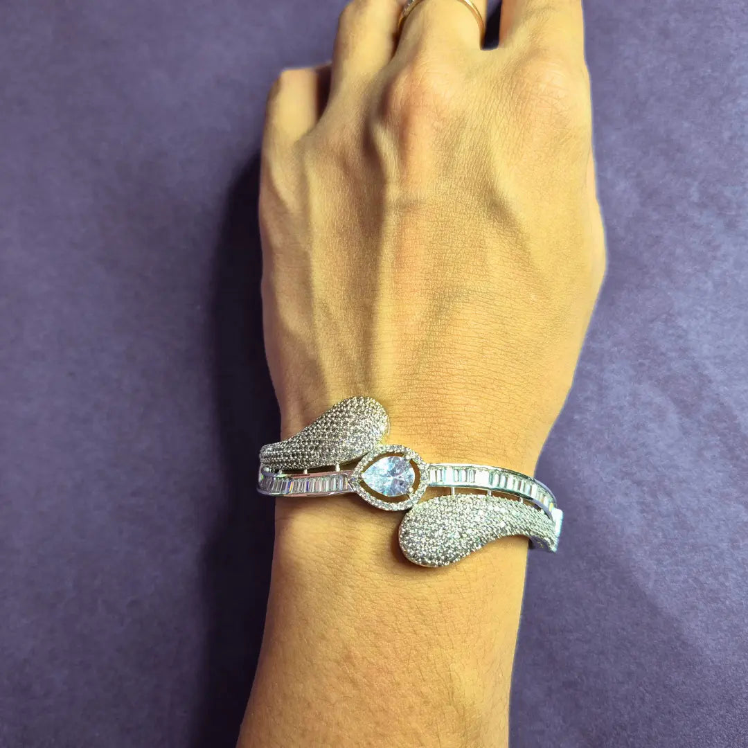 Woman wearing fixed size rhodium AD stone bracelet with a central gemstone on a wrist against a purple background