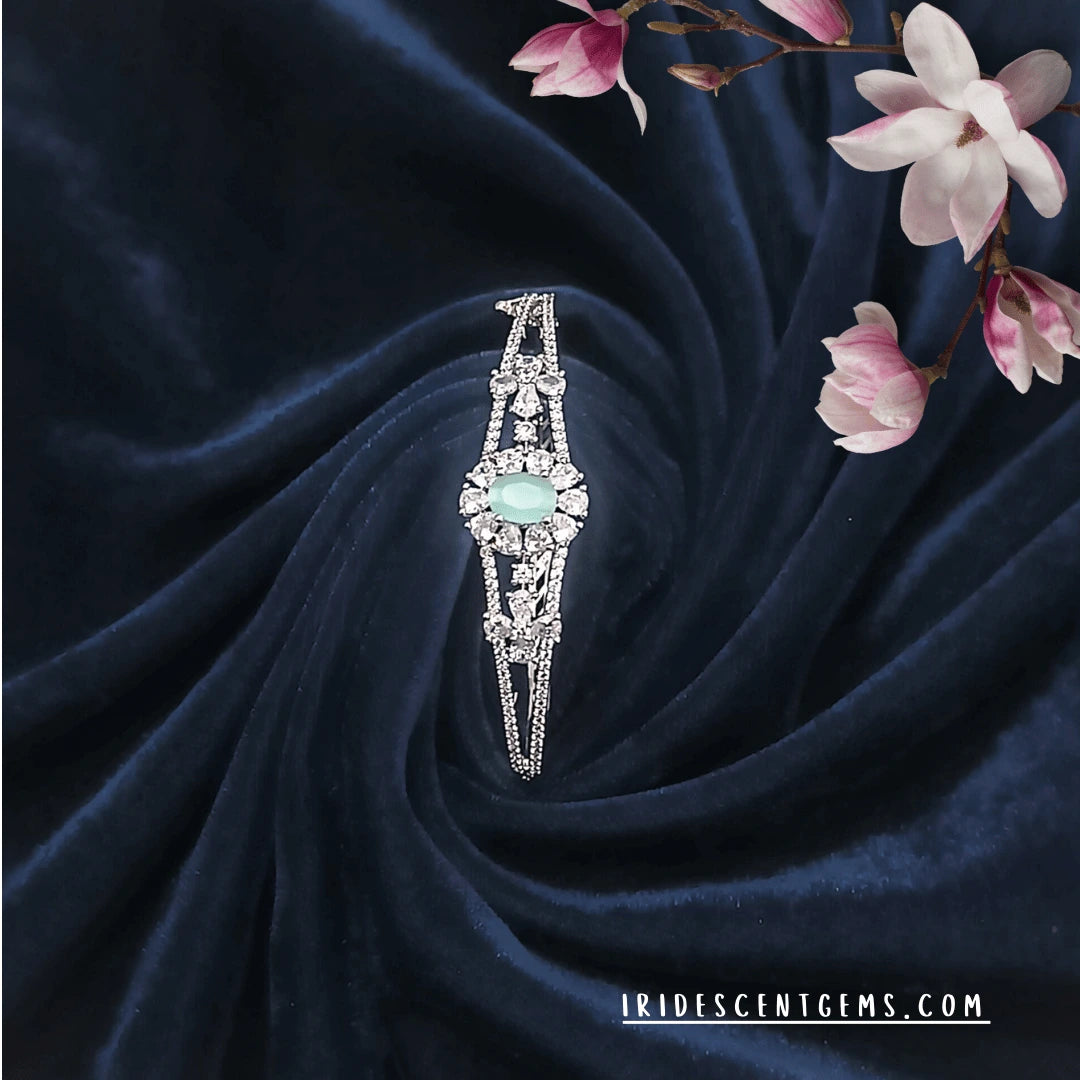 Fixed size silver bracelet with green AD stone centerpiece on blue velvet