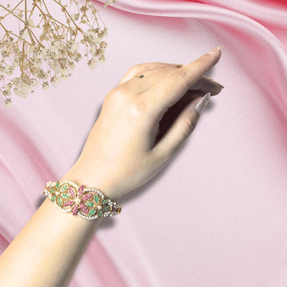 Traditional jadau bracelet on a pink fabric background with flowers.