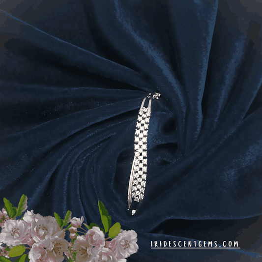 A sophisticated silver bangle adorned with sparkling diamonds, elegantly displayed on deep navy velvet fabric, complemented by delicate floral accents.