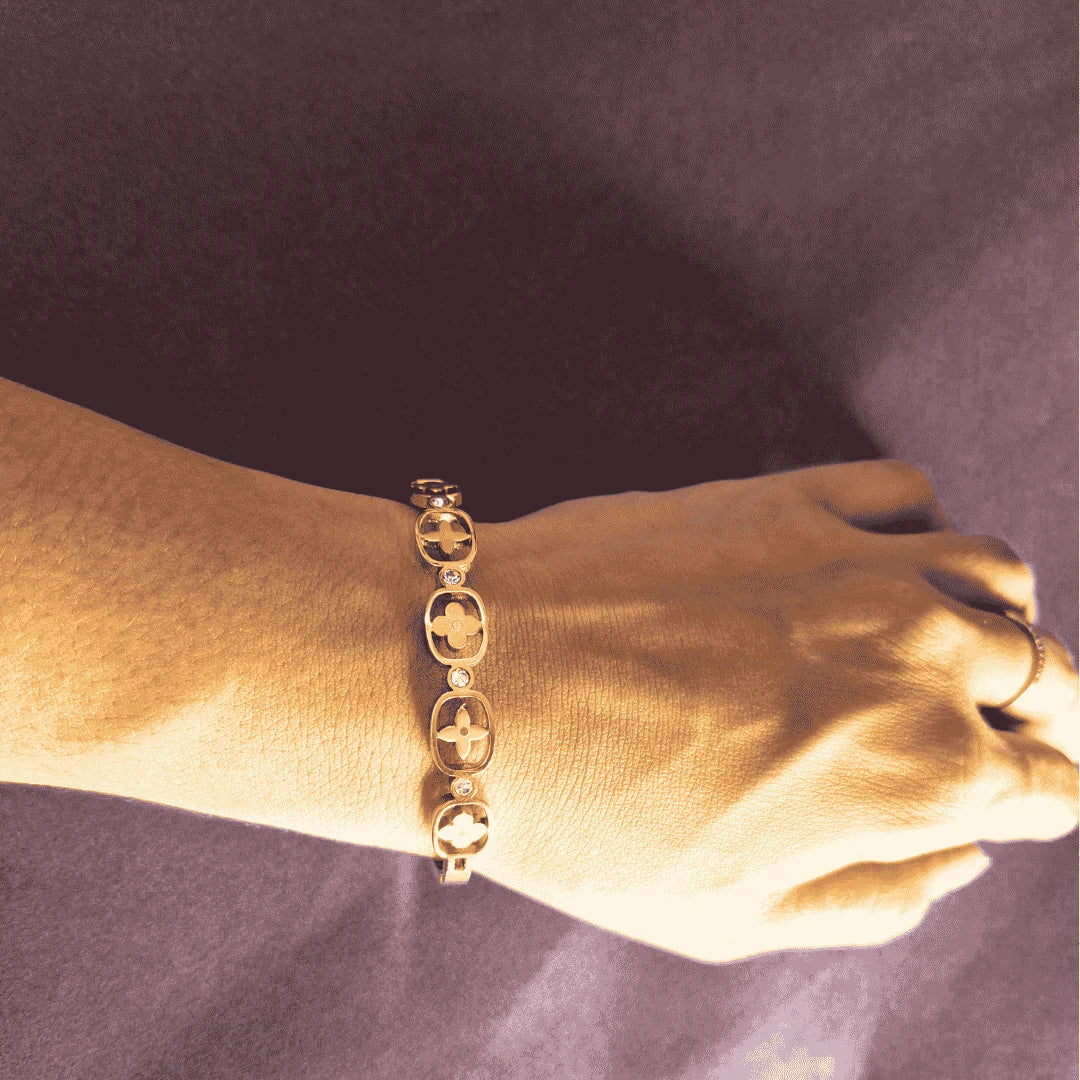 Gold bangle bracelet for women closeup view showing floral details on wrist