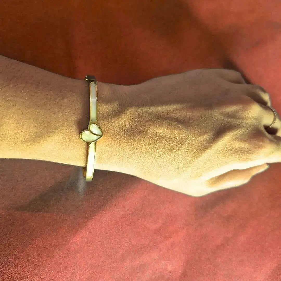 Gold plated bracelet for women heart detail worn on wrist with casual outfit