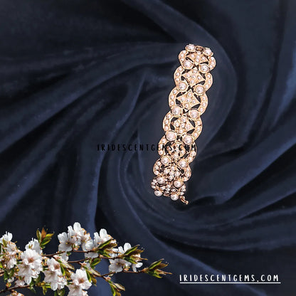 Gold jadau bracelet piece on a dark fabric background with floral elements